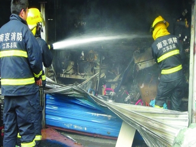 消防員撬開卷簾門救火。梅建明攝