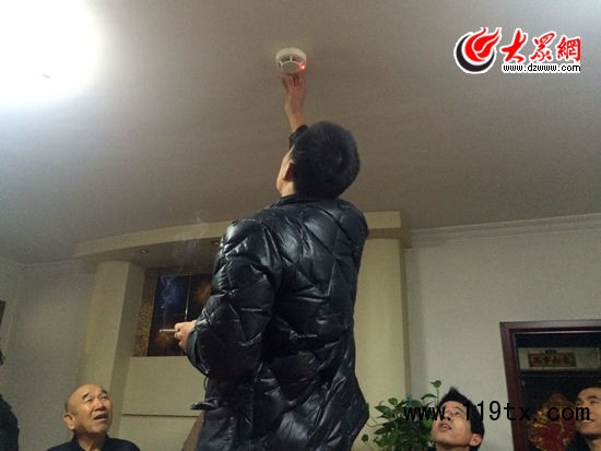 在居民家中試裝自動煙感報警器后,工作人員點燃一根香煙,報警器立刻亮起紅燈并發出警報